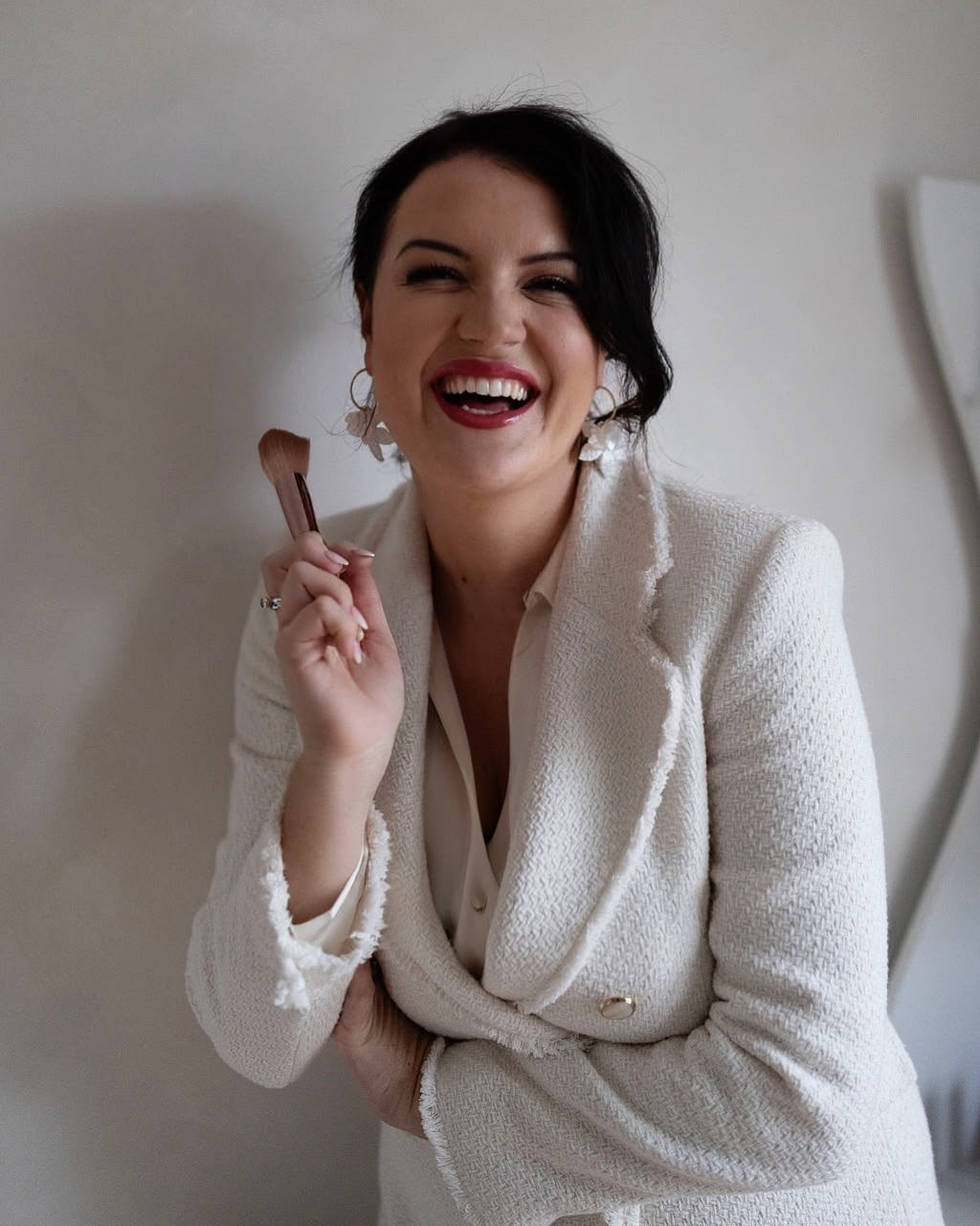 Becky of Rosebud Makeup & Beauty laughing and holding a makeup brush