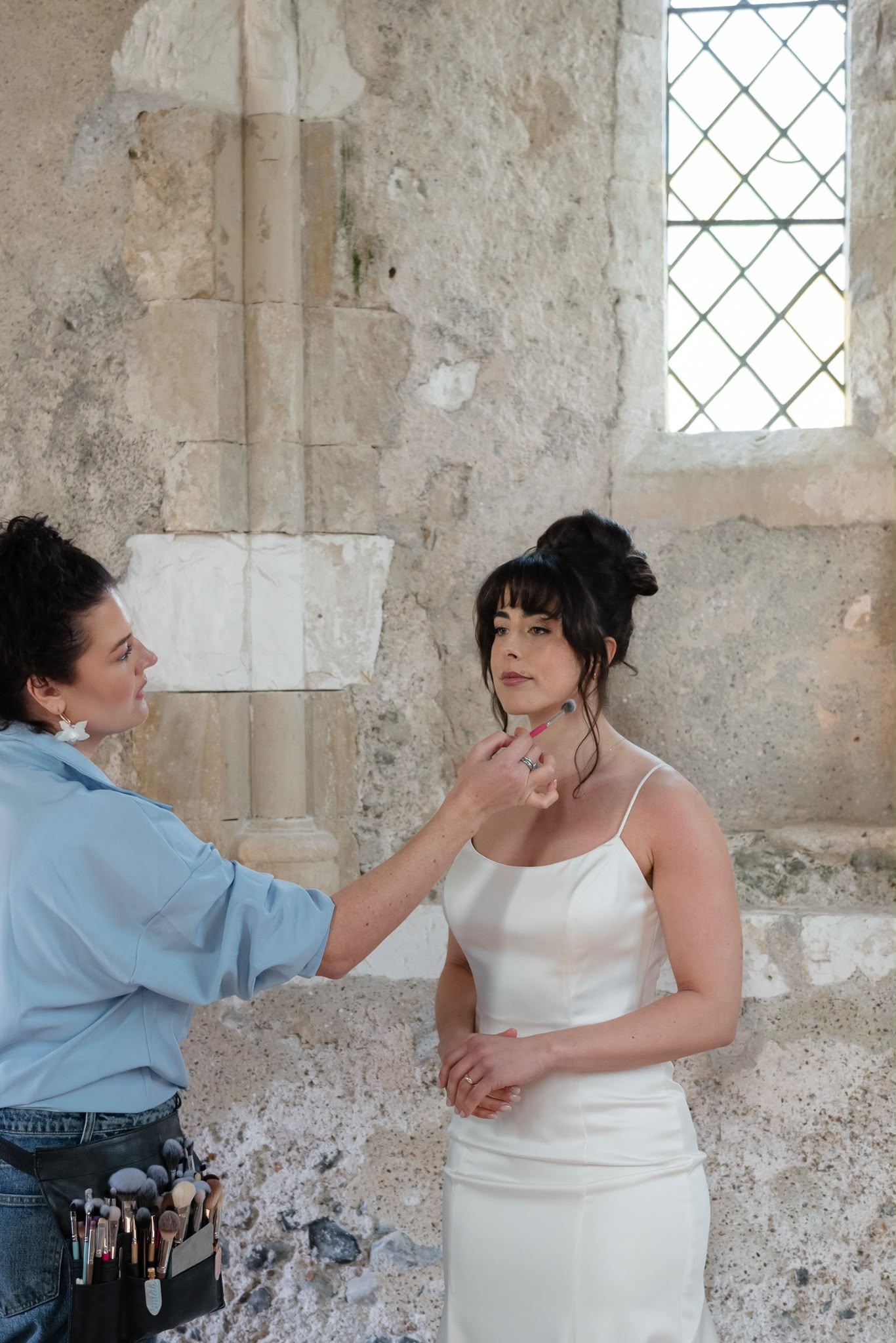 Becky applying bridal makeup in a historic stone venue