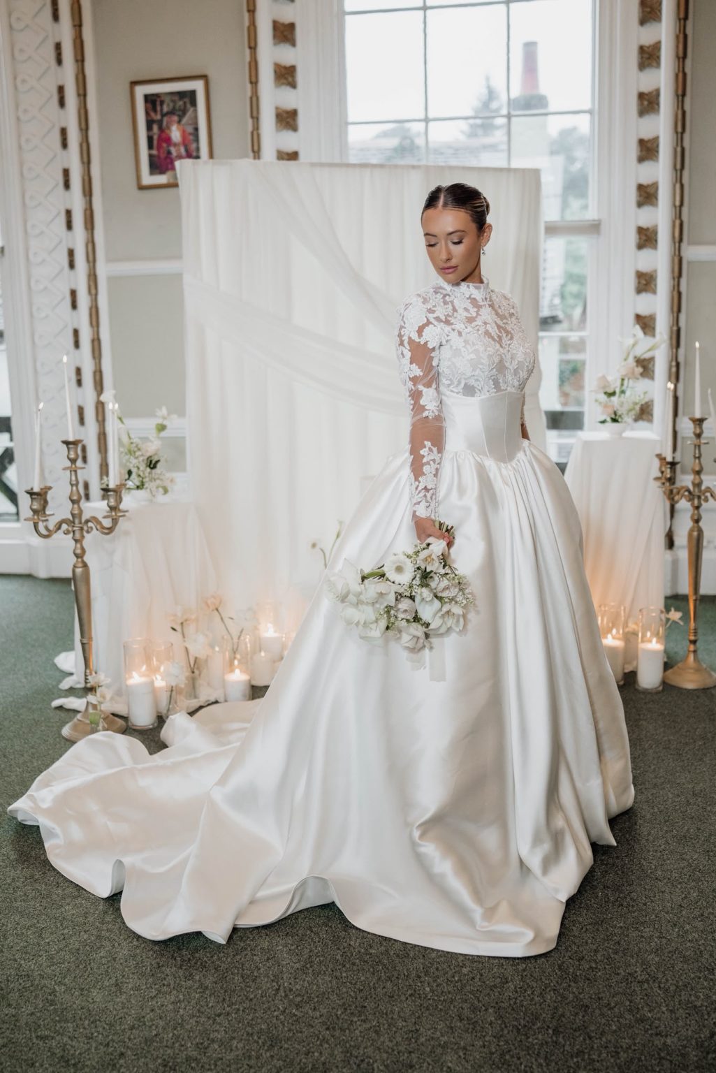 Bride in a lace and satin gown surrounded by candlelight