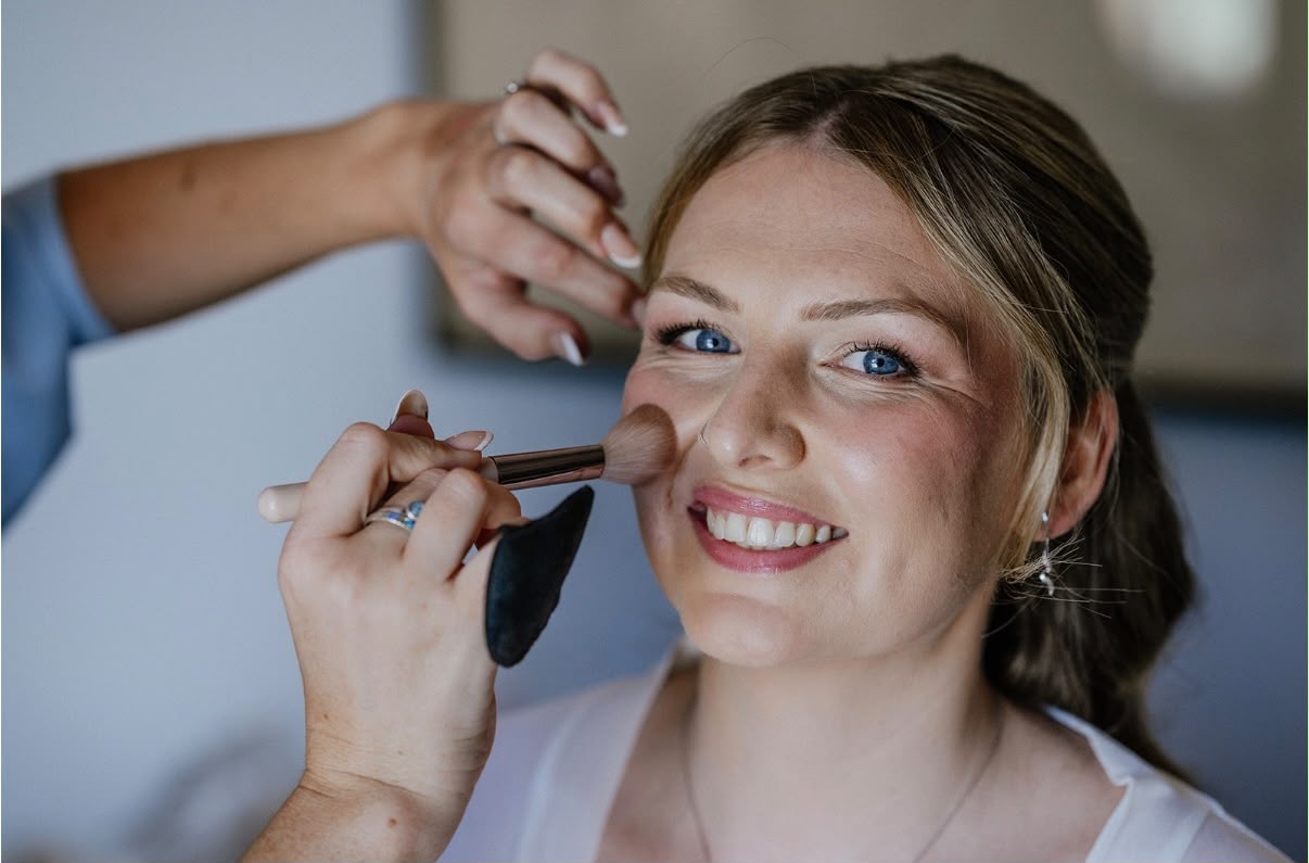 Blush being applied to a smiling client during a makeup lesson